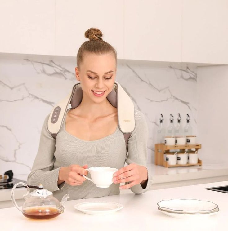 Woman wearing a neck and shoulder massager in a kitchen setting