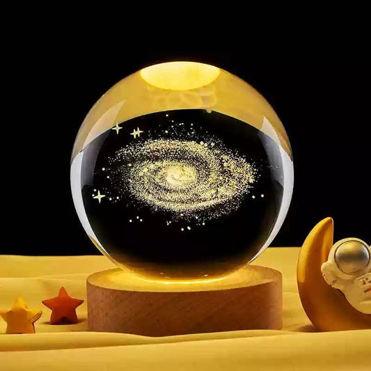 Glass ball with galaxy design on a wooden base against a black background