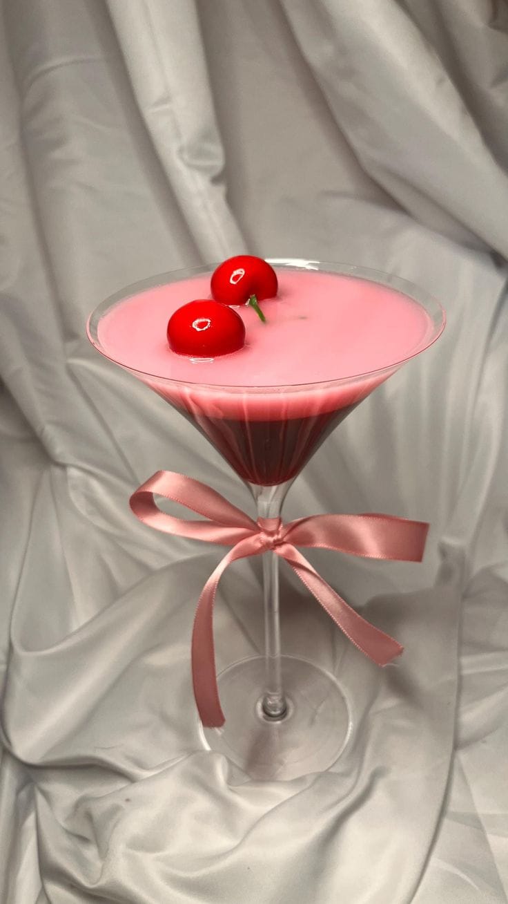 Pink cocktail with cherries and a pink ribbon on a gray fabric background