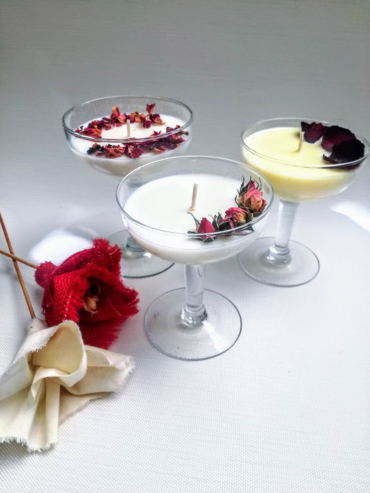 Three glass bowls with a white liquid and dried flowers on a light gray background