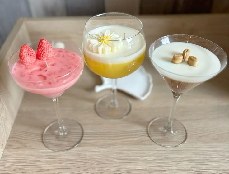 Three colorful cocktails on a wooden surface