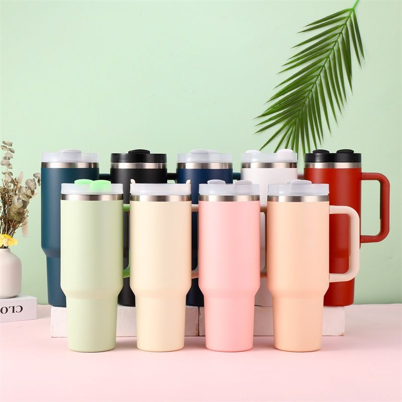 Set of colorful insulated travel mugs on a light green background with decorative elements.