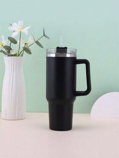 Black insulated mug with handle on a light surface against a light green background
