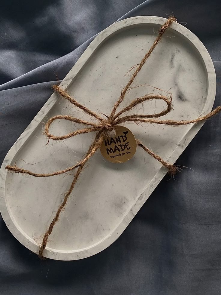 Concrete tray with twine and 'Hand Made' tag on a dark fabric background