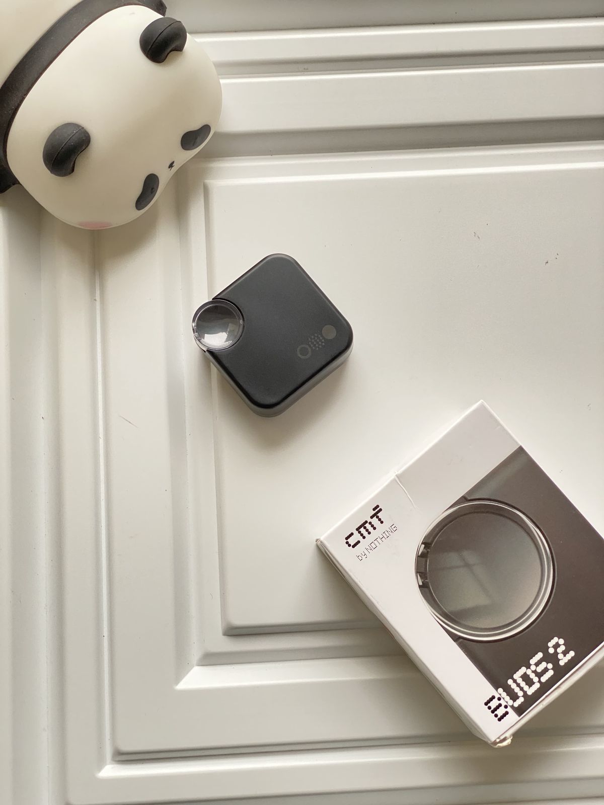 Black device and its packaging on a white surface with a decorative item.