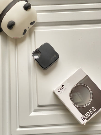 Black device and its packaging on a white surface with a decorative item.