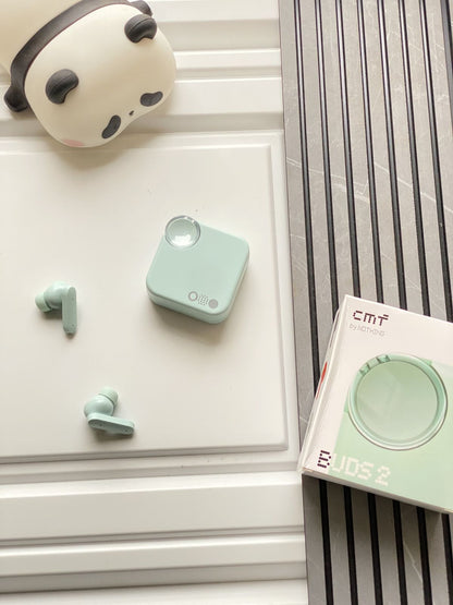 Green wireless earbuds with charging case on a white surface